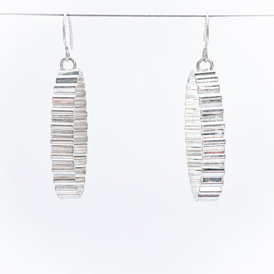 Large Corrugated Hoop Earrings by Judie Raiford hanging on wire