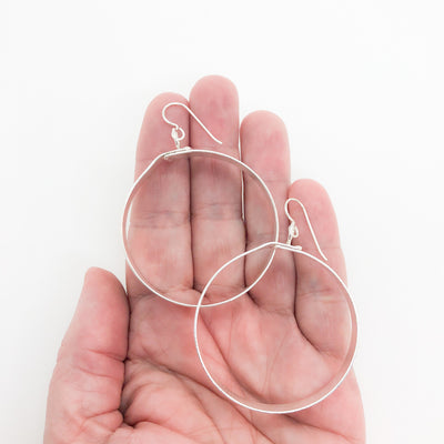 large sterling silver Full Moon Textured Bandage Hoop Earrings by Judie Raiford held in hand