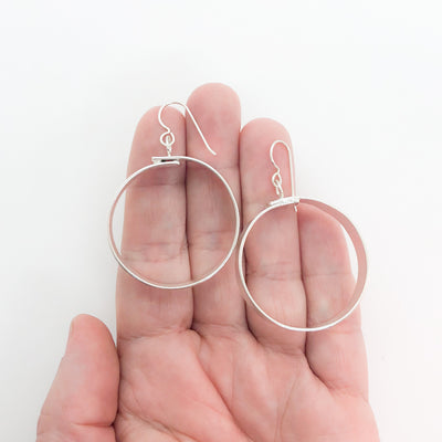 medium sterling silver Full Moon Textured Bandage Hoop Earrings by Judie Raiford held in hand