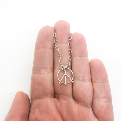 sterling silver Tiny Peace Sign Necklace by Judie Raiford held in hand