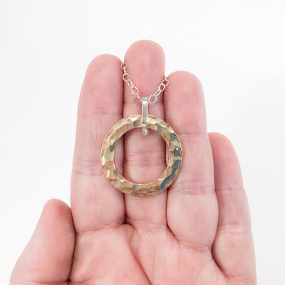 Sterling and 14k Gold Filled Ball Pein Hammered Circle Pendant Necklace by Judie Raiford held in hand