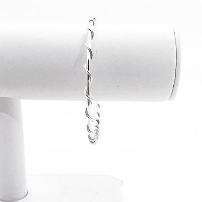 Single Wrapped Sterling Bangle by Judie Raiford on white jewelry display stand