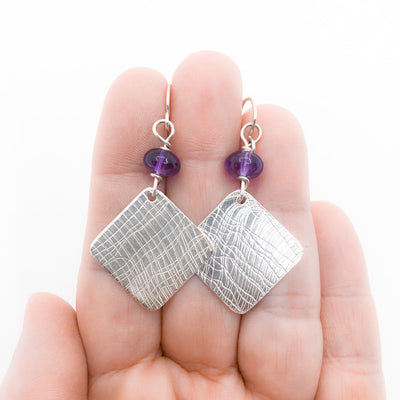 Sterling Goat Earrings with Upside Down Amethyst by Judie Raiford held in hand