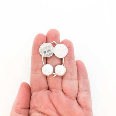 Sterling Silver Comet Earrings with White Coin Pearl by Judie Raiford held in hand