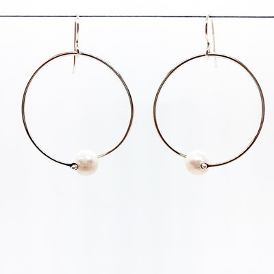 Sterling Twisted Hoop Pearl Earrings by Judie Raiford hanging on a wire