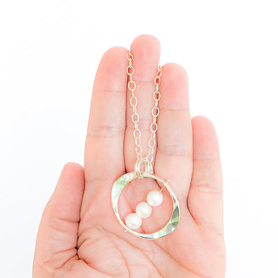 necklace in hand view of Large Naught Necklace with 3 White Pearls by Judie Raiford