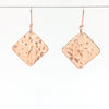 14k Rose Gold Ball Pein Square Earrings by Judie Raiford hanging on a wire