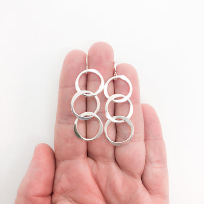 small sterling silver Hammered Triple Circle Earrings by Judie Raiford held in hand