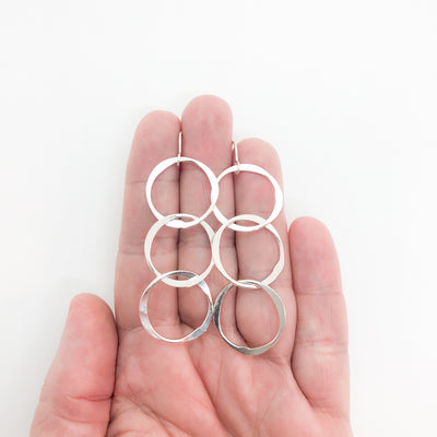 medium sterling silver Hammered Triple Circle Earrings by Judie Raiford held in hand