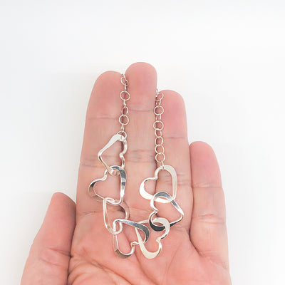 Hammered Sterling Silver 7 Heart Necklace by Judie Raiford held in hand