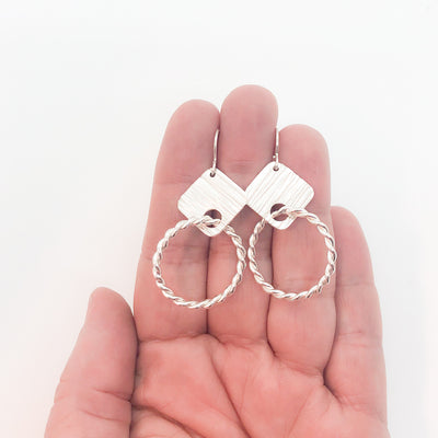 sterling silver Boiler Twister Hoop Earrings by Judie Raiford held in hand