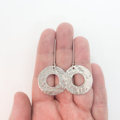 sterling silver Ball Pein Hammered Donut Earrings by Judie Raiford held in hand