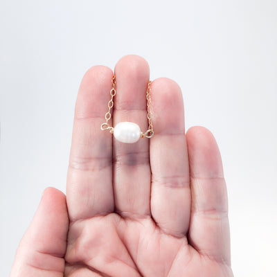 White Baroque Pearl on 14k Gold Chain Necklace by Judie Raiford held in hand