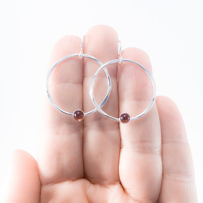 Sterling Baby Orbit Earrings with Garnet by Judie Raiford held in hand