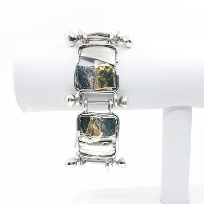 Sterling and 24k J Edgar Bracelet by Judie Raiford hanging on white bracelet display stand