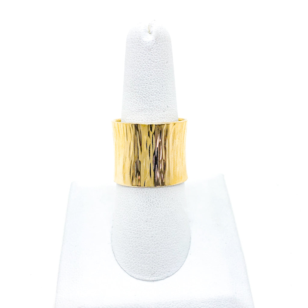 14k Gold Wide Hammered Band by Judie Raiford on white ring display stand