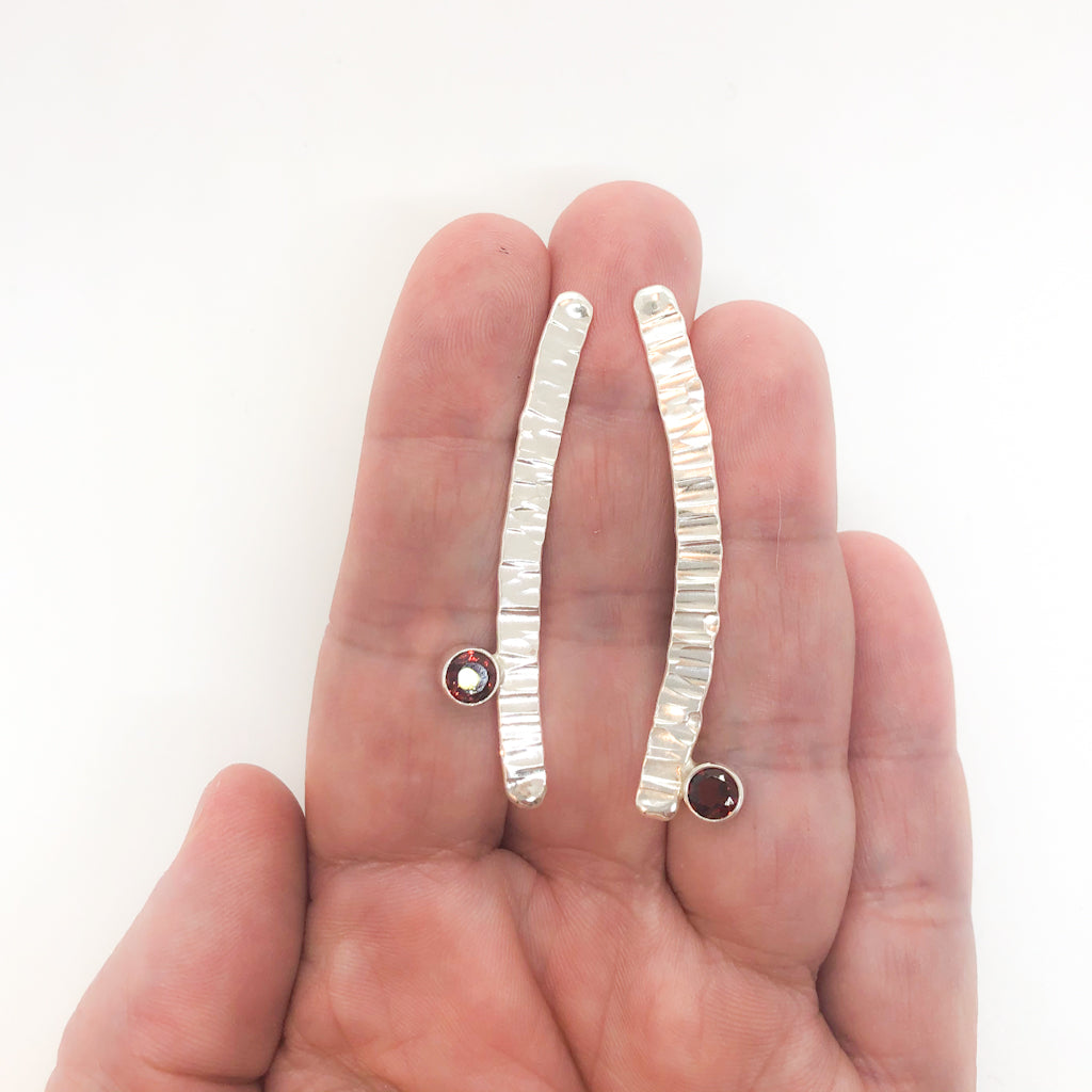 Sterling Short Arch Earrings with Garnet by Judie Raiford held in hand