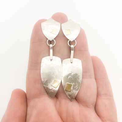 Sterling and 14k Shield Double Textured Earrings by Judie Raiford held in hand