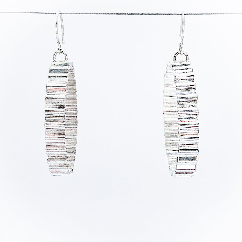 Large Corrugated Hoop Earrings by Judie Raiford hanging on wire