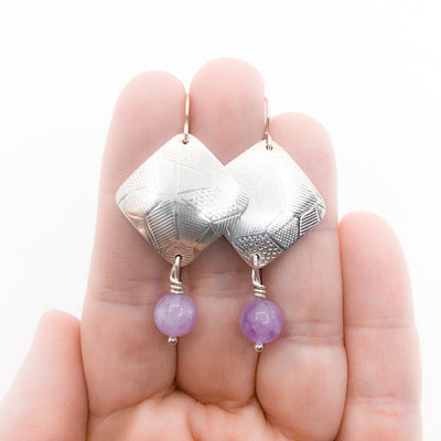 Sterling Goat Earrings with Cape Amethyst by Judie Raiford held in hand