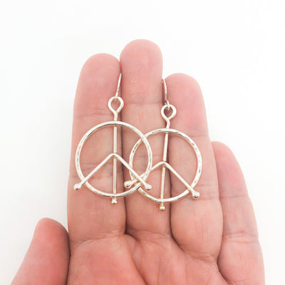 sterling silver Small Hammered Peace Sign Earrings by Judie Raiford held in hand