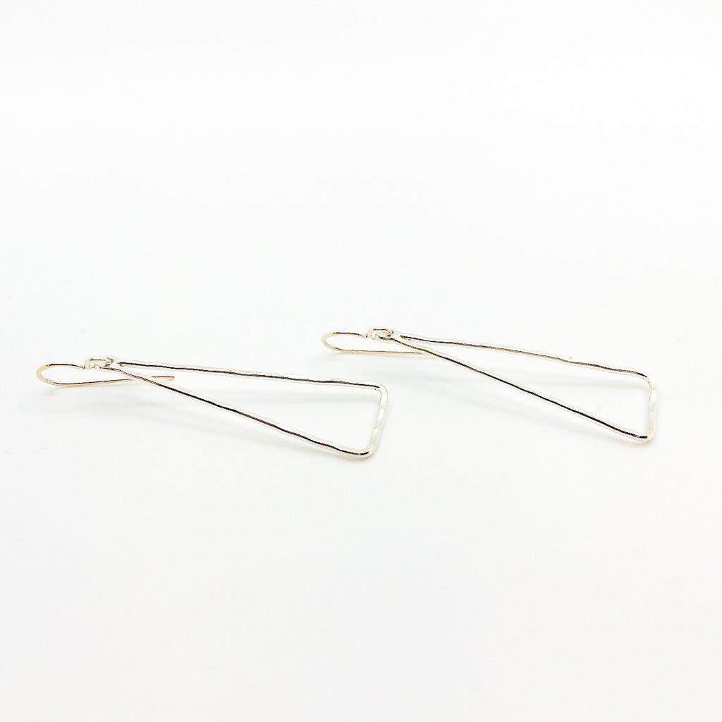 side angle view of Sterling Skinny Hammered Triangle Earrings by Judie Raiford