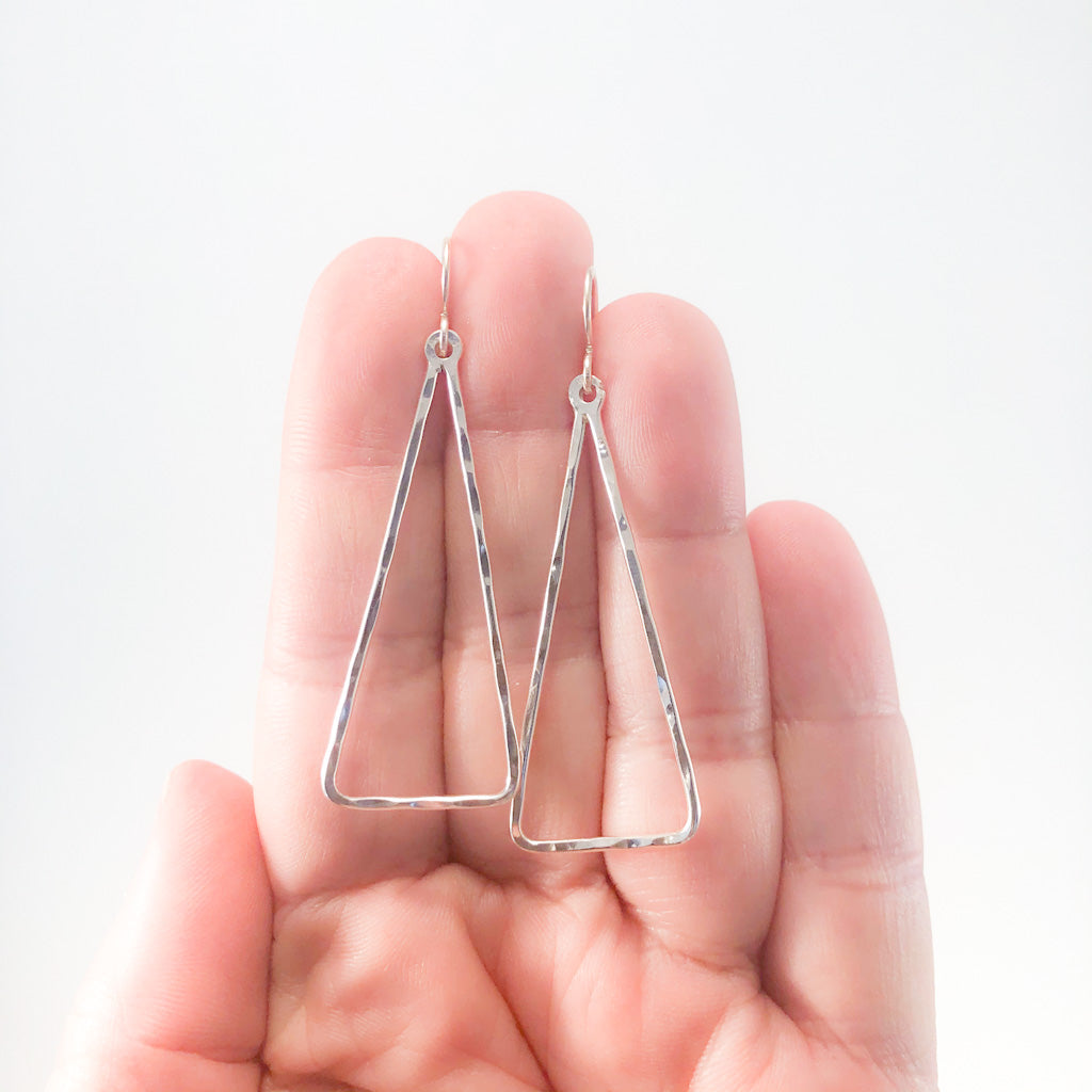 Sterling Skinny Hammered Triangle Earrings by Judie Raiford held in hand
