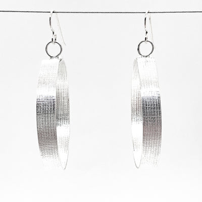large sterling silver Full Moon Textured Bandage Hoop Earrings by Judie Raiford hanging on wire