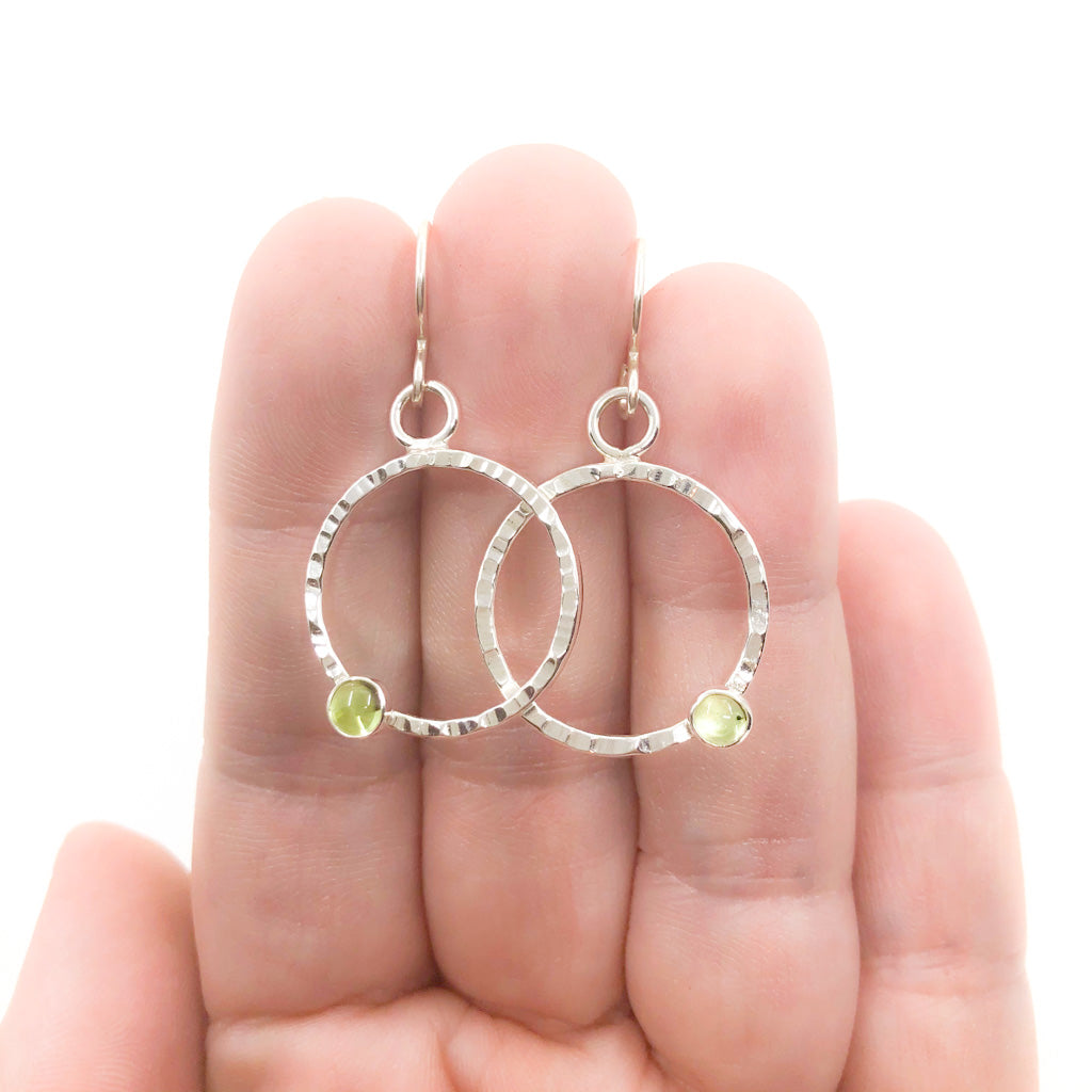 Sterling Pluto Earrings with Peridot by Judie Raiford held in hand