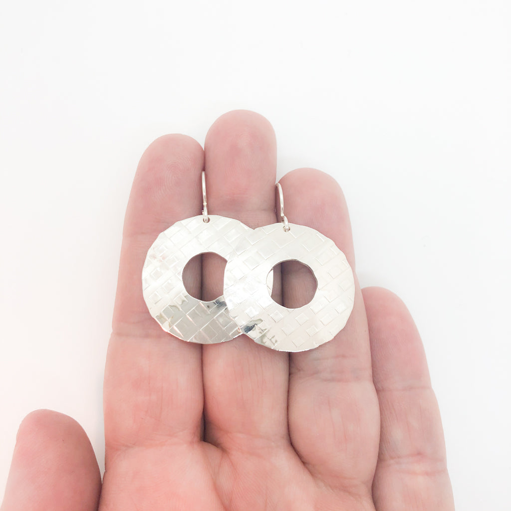 sterling silver Square Hammered Olive Earrings by Judie Raiford held in hand