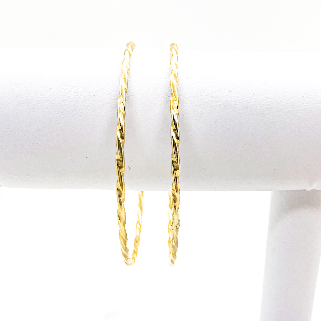 pair of 14k Gold Filled Single Twist Bangle by Judie Raiford handing on white bracelet display stand