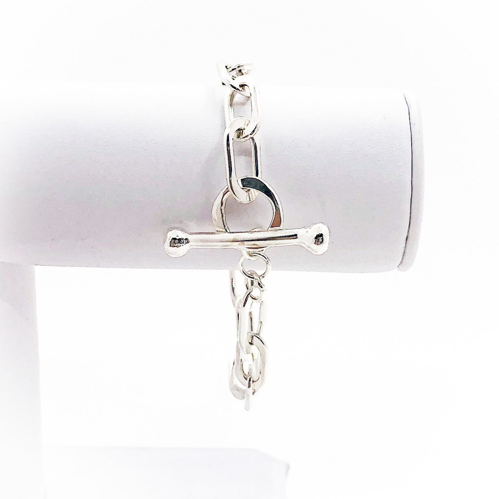 Sterling Tow Truck Junior Bracelet by Judie Raiford hanging on bracelet display stand