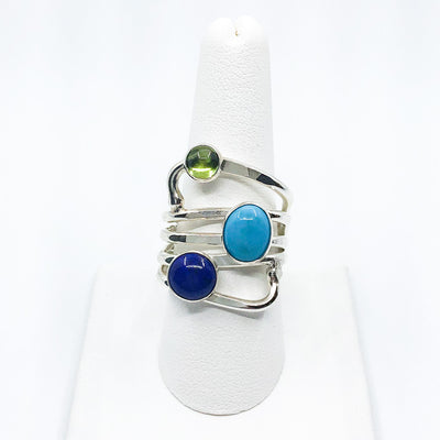 size 11 Sterling Wrap Ring with Peridot, Lapis, and Turquoise by Judie Raiford on white ring display stand