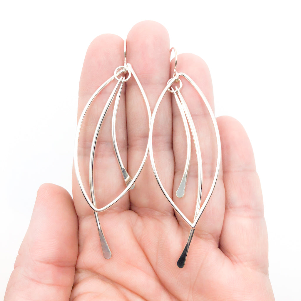 Sterling Large Paddle Bag Earrings by Judie Raiford held in hand