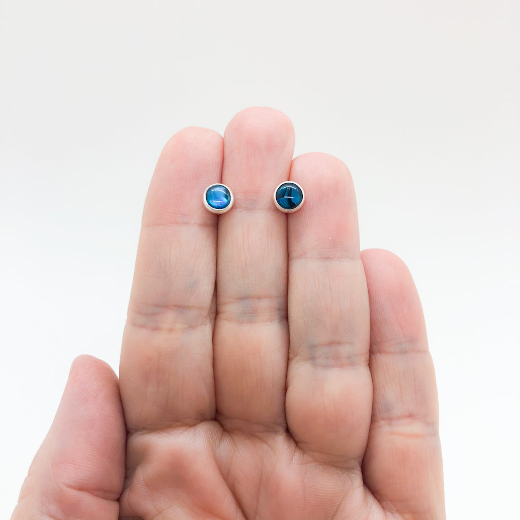 6mm Abalone Cabochon Stud Earrings by Judie Raiford held in hand