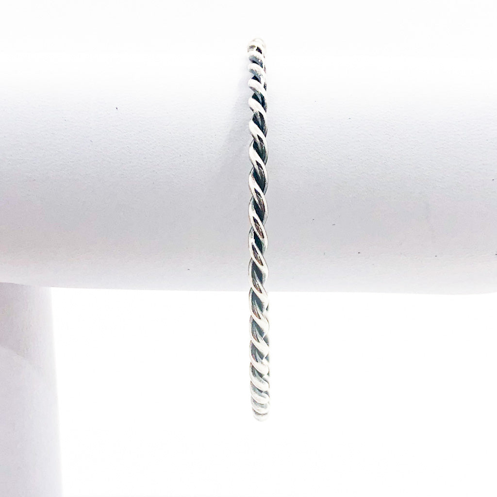 Double Twist Oxidized Sterling Bangle by Judie Raiford on white jewelry display stand