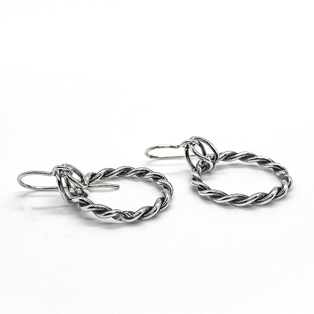 side angle view of polished and oxidized sterling silver Double Twist Hoop Earrings by Judie Raiford