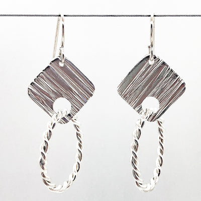 sterling silver Boiler Twister Hoop Earrings by Judie Raiford hanging on wire