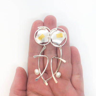 Sterling silver and 24k gold Asian Graphic Earrings with white Pearls by Judie Raiford held in hand