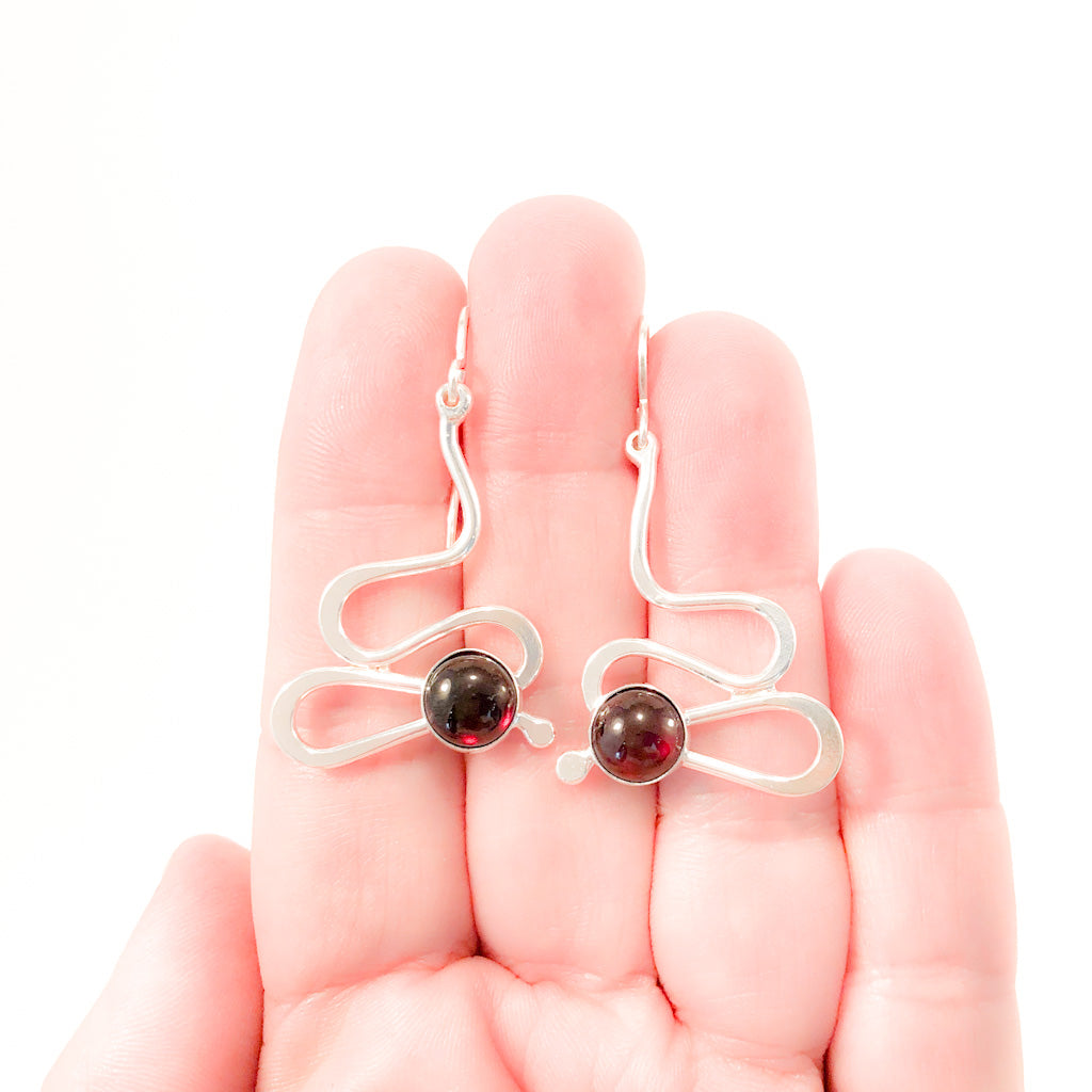 Sterling Touch of Romance Earrings with Garnet by Judie Raiford held in hand