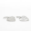 side angle view of flat lay view of Sterling Silver Small Hammered Heart Earrings by Judie Raiford