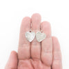 flat lay view of Sterling Silver Small Hammered Heart Earrings by Judie Raiford held in hand