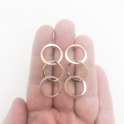 14k Gold Filled Hammered Triple Circle Earrings by Judie Raiford held in hand