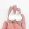 sterling silver Sinclastic Pear Shaped Earrings by Judie Raiford held in hand