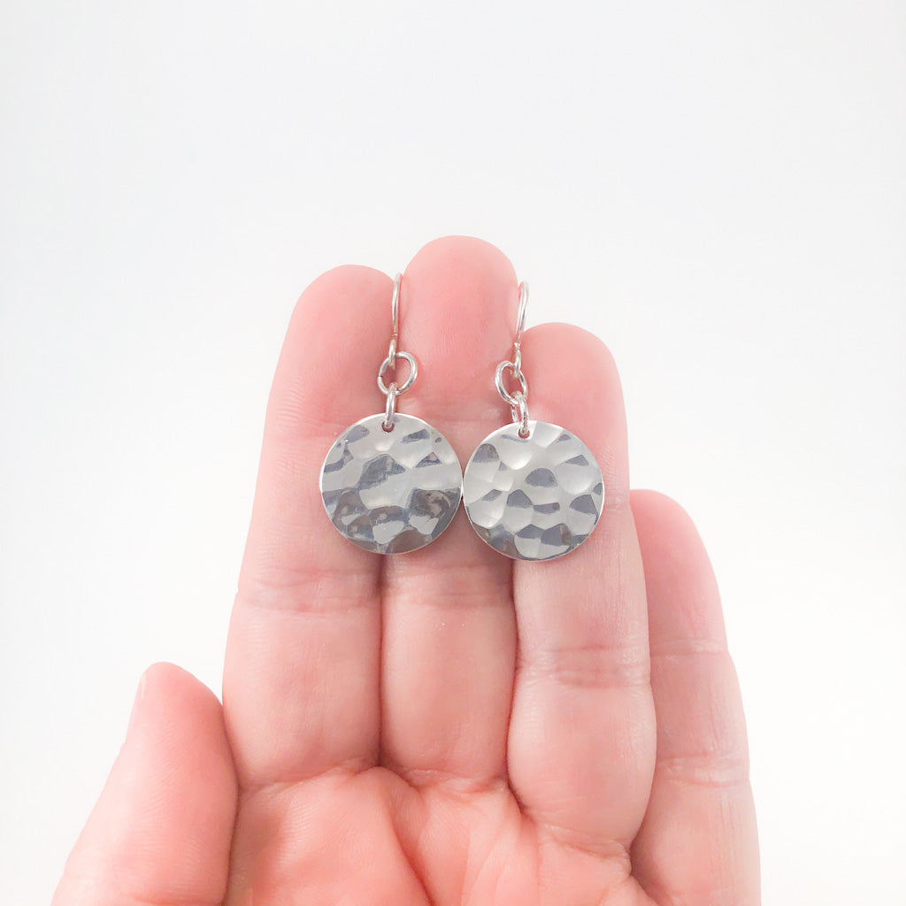 Sterling Flat Disc Ball Pein Earrings by Judie Raiford held in hand