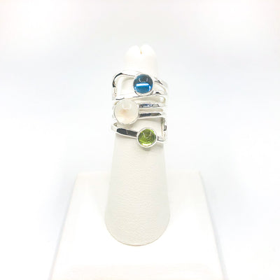 size 6.75 Sterling Wrap Ring with London Blue Topaz, Moonstone, and Peridot by Judie Raiford on white ring display stand