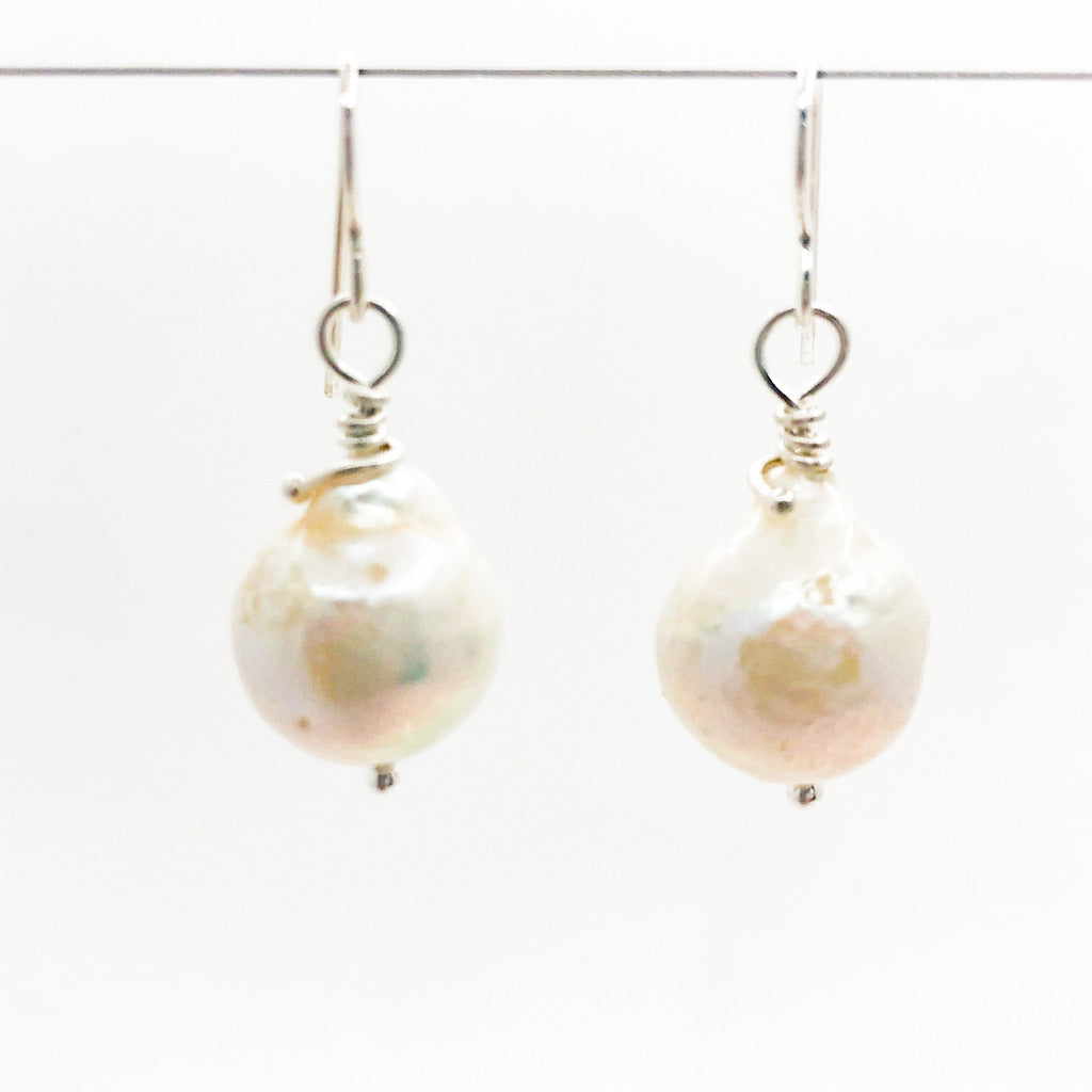 Large White Baroque Pearl Earrings by Judie Raiford hanging on wire