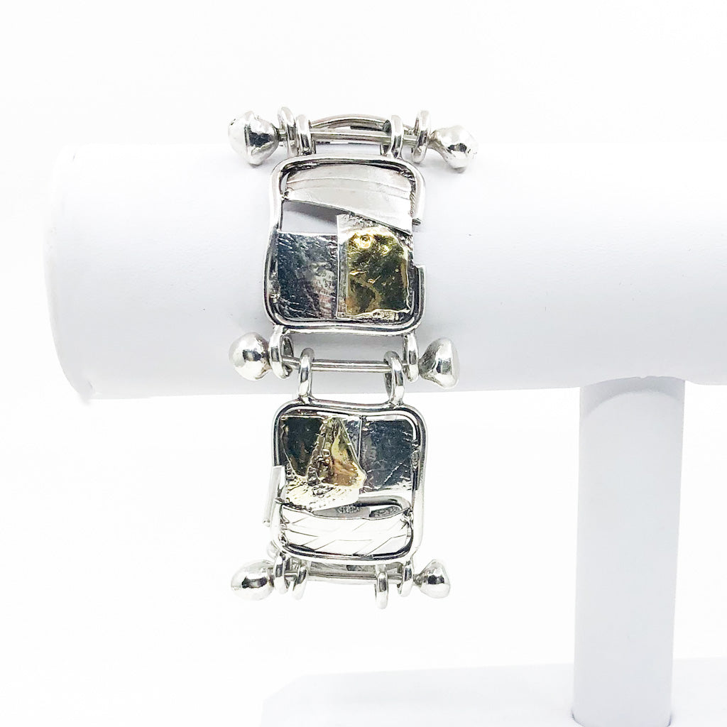 Sterling and 24k J Edgar Bracelet by Judie Raiford hanging on white bracelet display stand
