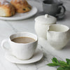 white latte cup and saucer with coffee and croissants on marble counter