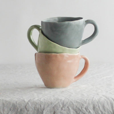 stack of blush, celery, and indigo glazed latte cups by Nona Kelhofer